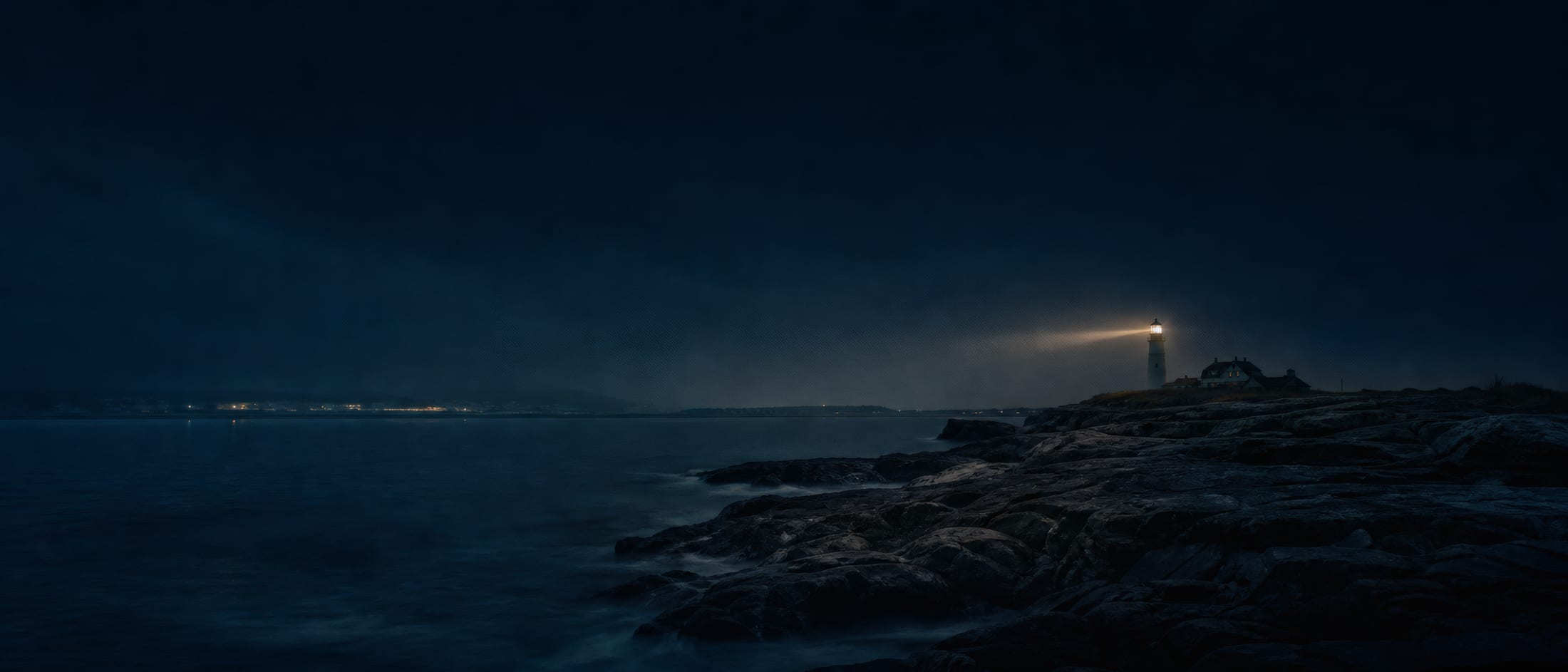 A lighthouse sweeping its beam over the dark Rhode Island coast at night